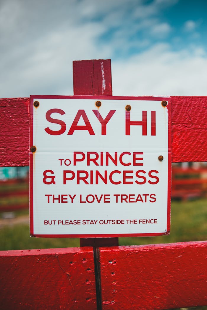 A welcoming red and white sign on a wooden fence suggests greeting animals named Prince and Princess.